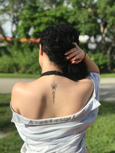 the back of a woman's neck with a flower tattoo on her left shoulder