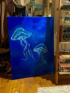 a painting of two jellyfish on a blue background in front of a rack of books