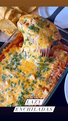 a cheesy enchiladas being lifted from a casserole dish