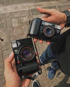 two people holding old cameras in their hands