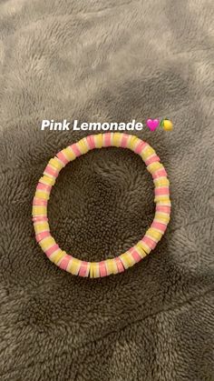 the pink lemonade bracelet is laying on top of a gray blanket with hearts and candy