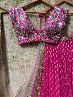 A three-piece fuchsia mirror zari lehenga set from the Priti Sahni collection. This gorgeous georgette fuchsia butti lehenga with a heavy zari border of sequin work is paired with a raw silk fuchsia mirror blouse in pearl, and zardozi hand embroidery. The lehenga has side hanging ball tassels to the waistline. And the blouse has pearl tassel tie-up at the back. This outfit is completed with a hand-embroidered butti nude tulle dupatta in net material with gota-sequin-pearl work border detail. Nude Lehenga, Off Shoulder Lehenga, Lehenga Designs Latest, Gold Lehenga, Raw Silk Lehenga, Georgette Lehenga, Yellow Lehenga, Rani Pink, Color Mirror