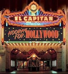 the hollywood sign is lit up in front of a theater building at night with bright lights