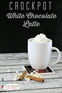 a white coffee cup filled with whipped cream and cinnamon on top of a wooden table