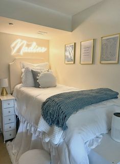 a white bed sitting in a bedroom next to two pictures on the wall above it