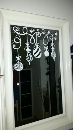 a window decorated with christmas ornaments and baubles hanging from it's side