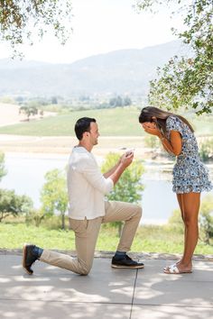 a man kneeling down next to a woman who is holding a cell phone in her hand