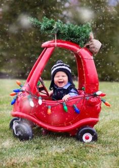 a small child in a red car with christmas lights