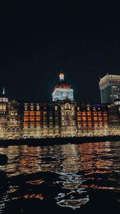 a large building sitting on top of a river next to a tall building at night