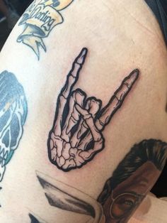 a man's arm with tattoos on it that has a hand holding a knife