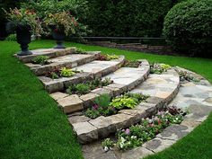 an outdoor garden with stone steps and flowers in the center, surrounded by green grass