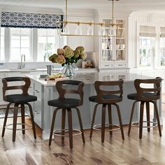 a kitchen with four stools in front of the counter and an island that has flowers on it