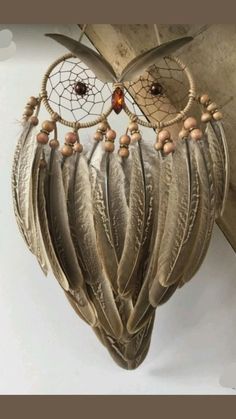 an owl shaped dream catcher hanging from a wooden beam with beads and feathers on it