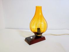 a yellow glass lamp sitting on top of a wooden base