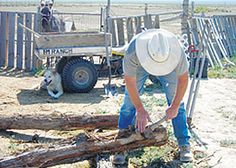 a man in a cowboy hat is working on a log