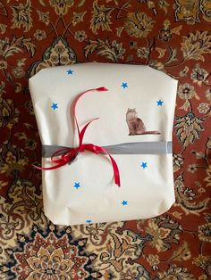 a wrapped gift with a cat on it and a red ribbon tied around the edge