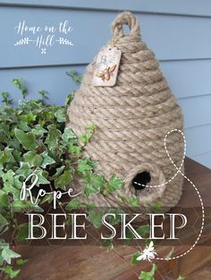 a bee house made out of rope on top of a wooden table next to a potted plant