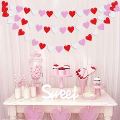 a table topped with lots of pink and red heart shaped desserts on top of it