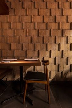 a wooden table and chair in front of a wall made out of blocks with plates on it