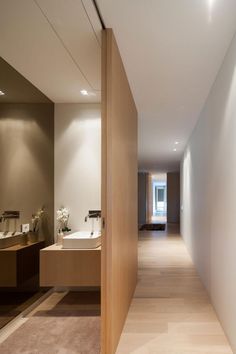 a long hallway leading to two sinks in a bathroom with wood paneling on the walls