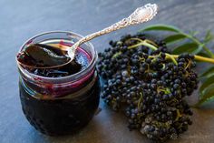 a jar filled with blackberries next to a spoon