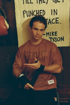 a young man is standing in front of a sign that says, i'll they get punched in face mike tyson