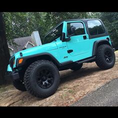 a blue jeep is parked in front of a tree