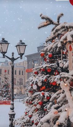 a christmas tree in the middle of a snowy street with lights and decorations on it