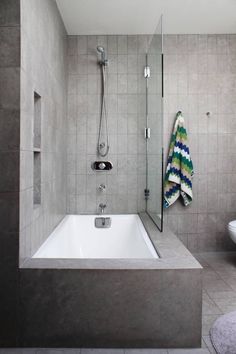 a bathroom with a bathtub, toilet and shower head mounted to the side of the wall