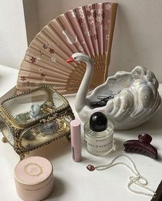 a white table topped with a pink fan and other items next to a small box