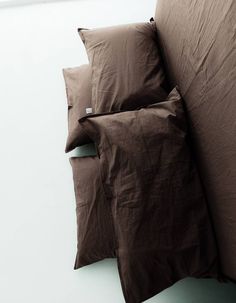 two brown pillows sitting next to each other on top of a bed