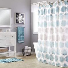 a bathroom with blue and white decor on the shower curtain, rugs and mirror