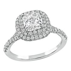 a cushion cut diamond ring with double halos on the shoulders and sides, set in white gold