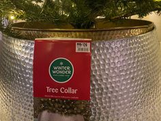 a christmas tree in a silver pot with a red label on it's side