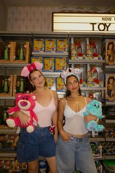 two young women holding stuffed animals in front of toys