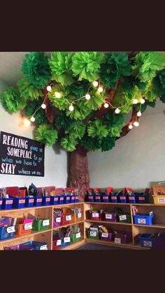 a tree with lights hanging from it's branches in a room filled with children's books