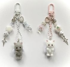 two key chains with small stuffed animals attached to them, one is pink and the other is white