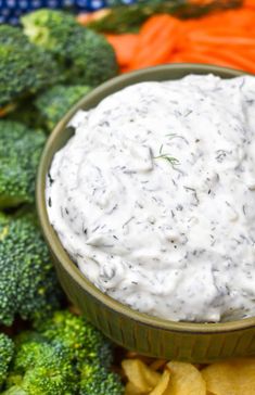 a bowl of dip surrounded by broccoli and carrots