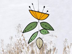 a wind chime hanging from the side of a snow covered field with tall grass