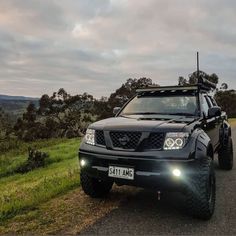 a black four - doored truck driving down a country road with its lights on