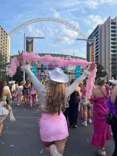 a woman in a pink dress and white cowboy hat is dancing with her hands up