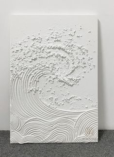 an abstract white painting with waves and dots on the surface, in front of a wall