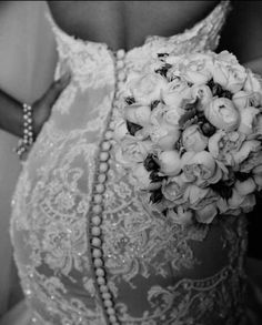 a woman in a wedding dress holding a bridal bouquet with pearls on the side