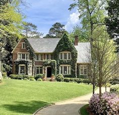 a large brick house with ivy on the front and side walls, surrounded by lush green grass