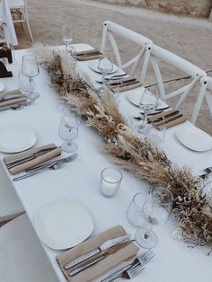 the table is set with white plates and silverware, napkins and place settings