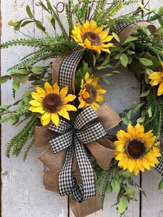 a wreath with sunflowers and greenery hanging on a door