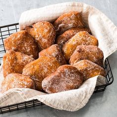 a basket filled with sugar covered donuts on top of a table