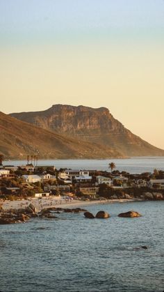 a beach with houses and mountains in the background