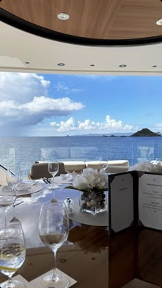 there are many wine glasses on the table and in front of the ocean with white flowers