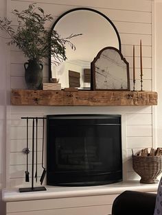 a living room with a fireplace, mirror and vase on top of the mantel